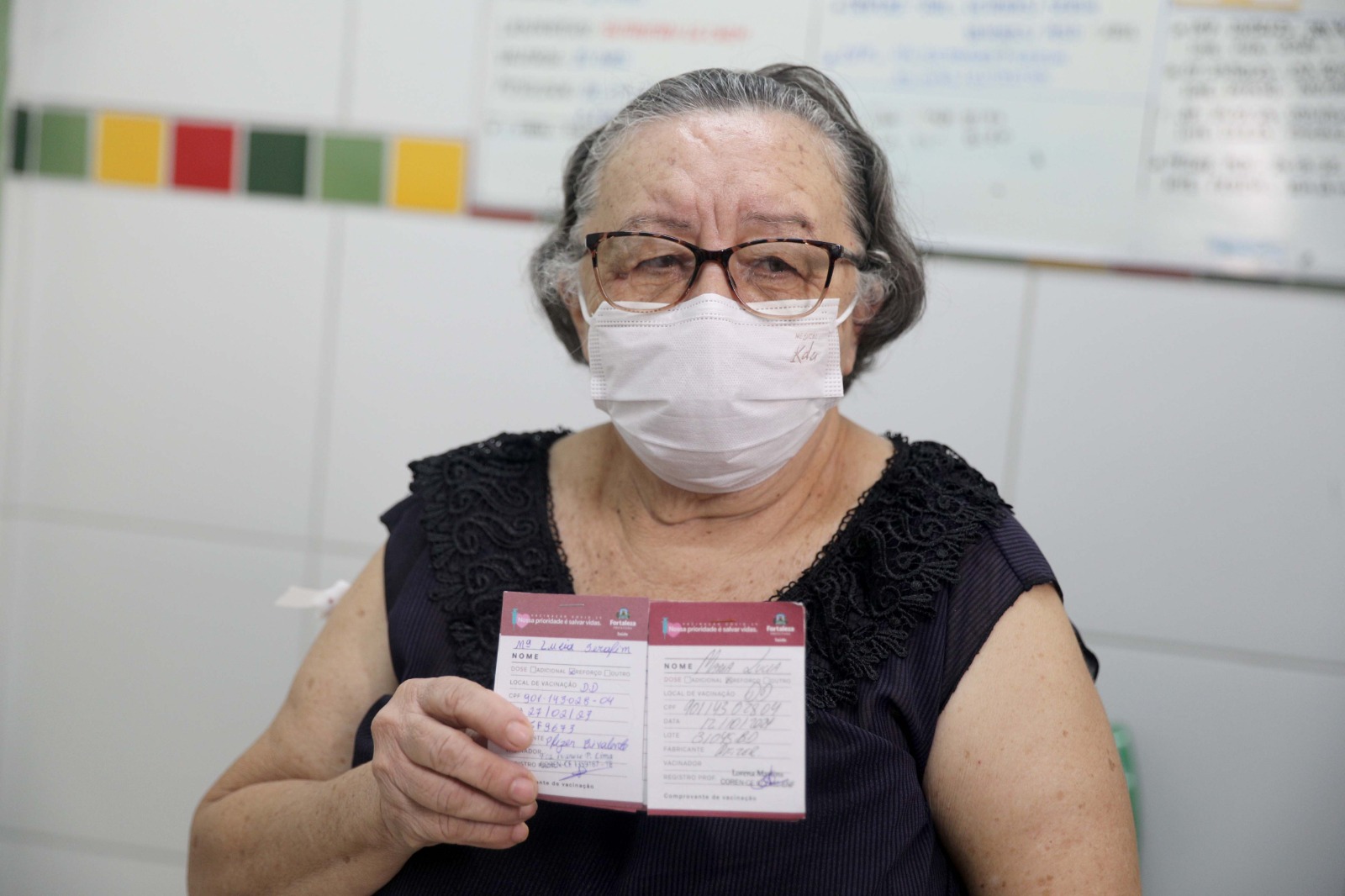 Maria Lucia Serafim posa para a foto com seu cartão de vacinação